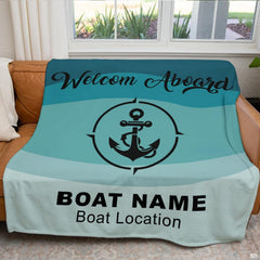 Teal nautical anchor blanket arranged neatly across brown leather living room sofa