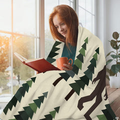 Bigfoot pine tree throw blanket styled neatly across a living room sofa.