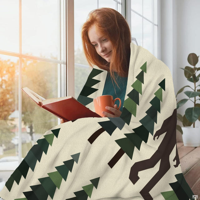 Bigfoot pine tree throw blanket styled neatly across a living room sofa.