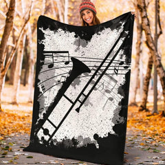 Angled view showing neat hemmed border on black and white trombone music blanket.