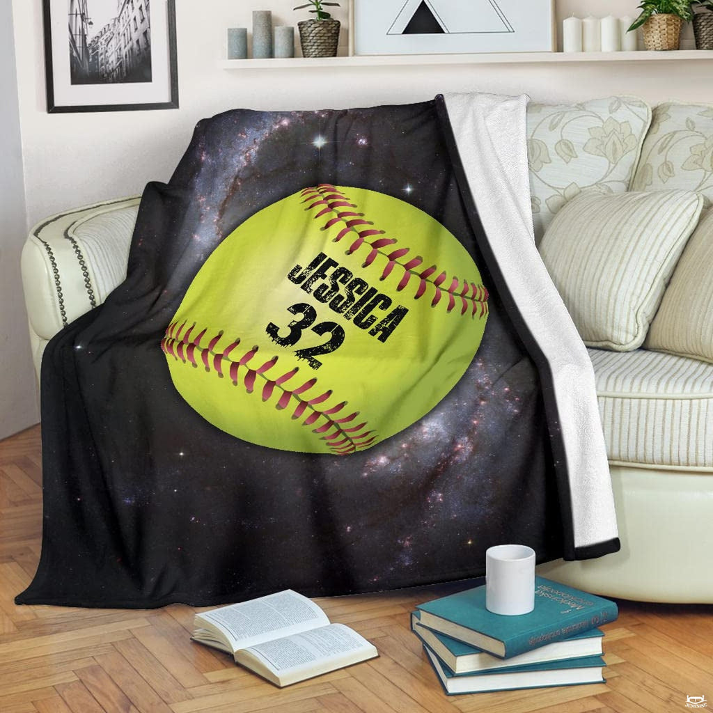 Galaxy fastpitch optic ball blanket draped over sofa beside books