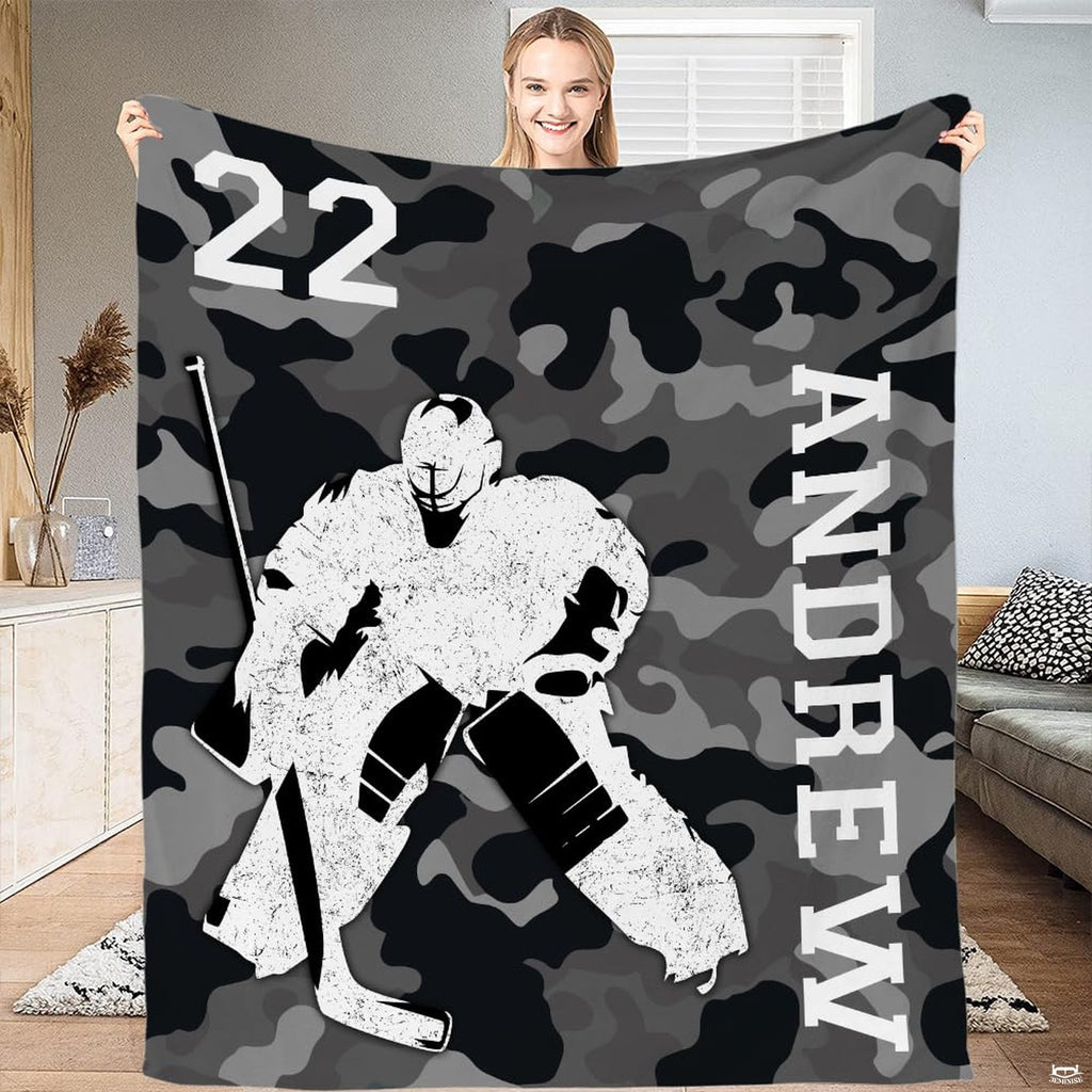 Upright display of camo hockey goalie artwork held by a woman showing netminder silhouette and camo.