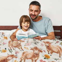 Overhead view of repeating highland cow and botanical blossom pattern across bedding set.