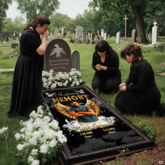 Solemn cemetery setting with mourners in dark attire kneeling beside the celestial angel wings tribute.