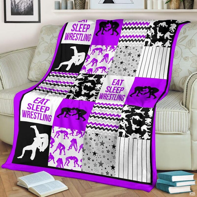 Purple wrestling patchwork blanket draped over a living room couch beside a stack of books.