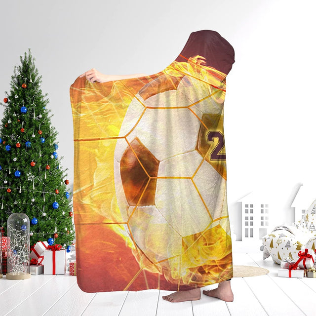 Flaming soccer sports blanket worn in a living room near a holiday Christmas tree and gift boxes.