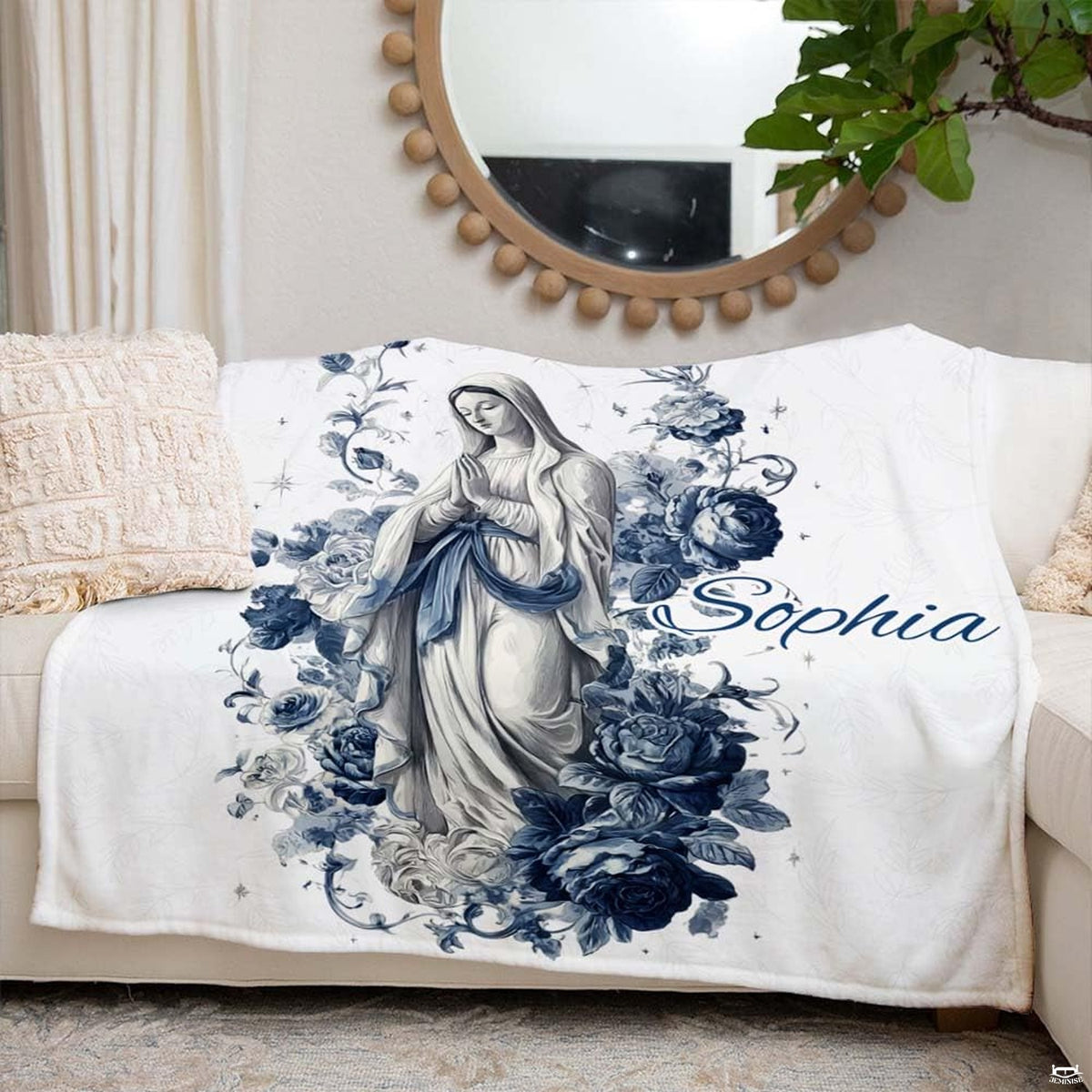 Catholic floral Blessed Mother blanket styled neatly across an ivory living room couch.