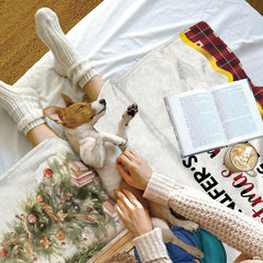 Cozy bed setting featuring puppy napping beside folded watercolor holiday parlor throw blanket.