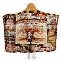 Book lover throw blanket featuring an illustrated reader under a book-leaf tree with library vignettes