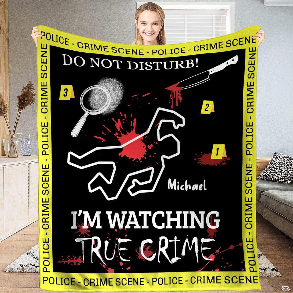 Woman holding up black crime scene blanket featuring chalk outline and yellow police tape