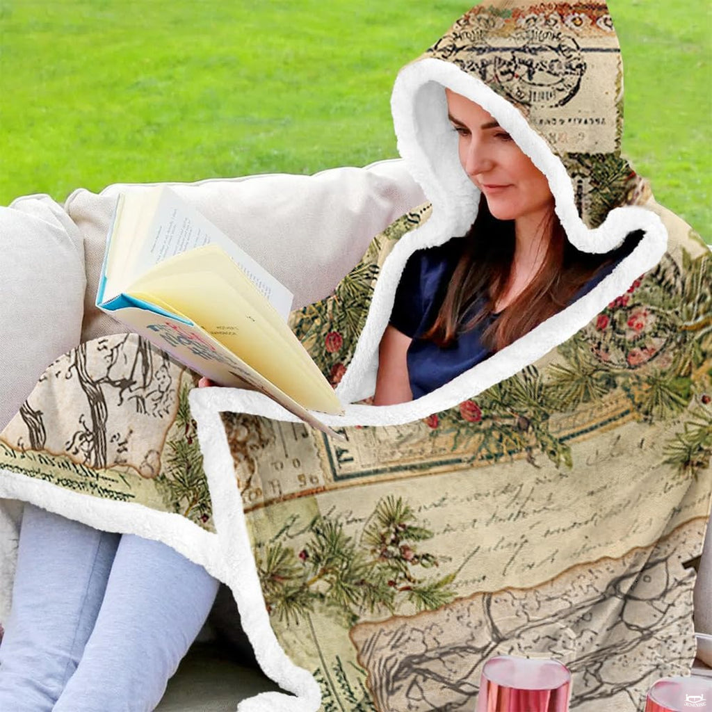 Woman wearing the hooded wrap reading an open book outside on a patio couch.