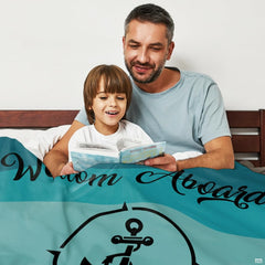 Father and child reading storybook in bed covered by coastal teal nautical blanket
