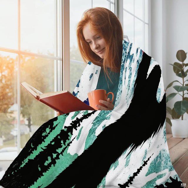 Woman wrapped in patriotic Sasquatch blanket reading a book by sunlit window