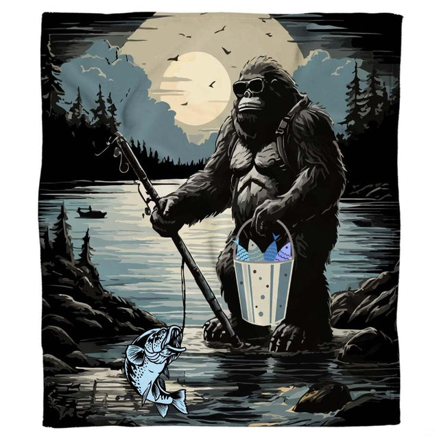 Graphic blanket artwork showing Bigfoot wearing sunglasses holding a fishing rod and fish bucket in a mountain lake.