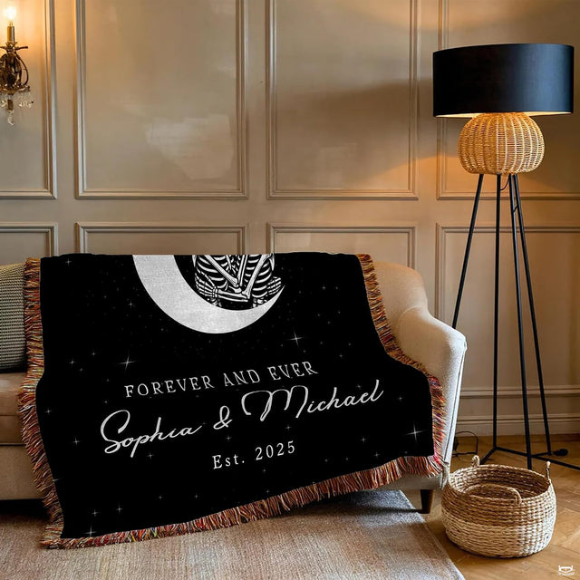 Close-up of embracing skeleton couple artwork nestled inside a luminous white crescent moon on a blanket