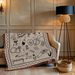 Close-up of wedding line art drawings including tiered cake, champagne glasses, and wedding rings on a blanket