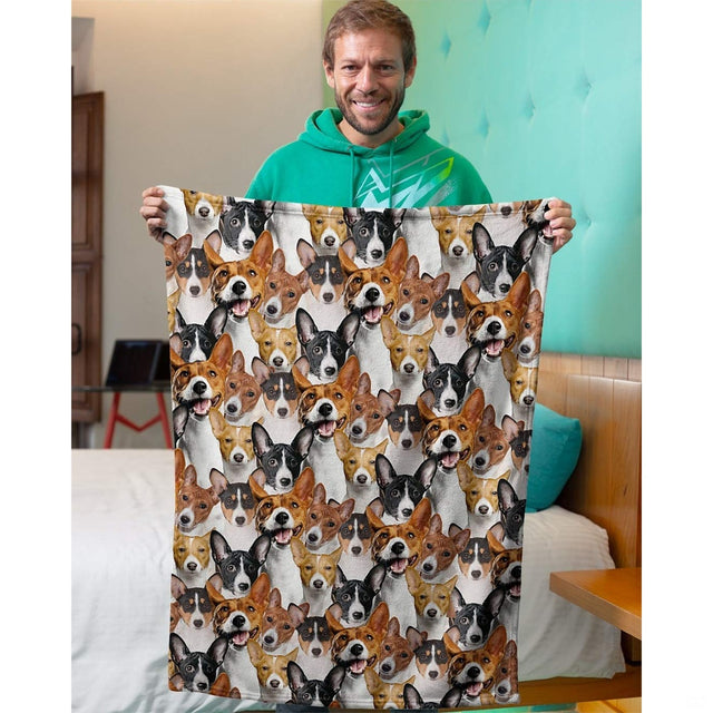 Model holding up a Basenji dog collage blanket in an indoor bedroom setting.