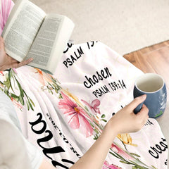 Faith-inspired floral cross artwork folded neatly across indoor seating beside an open book and coffee cup
