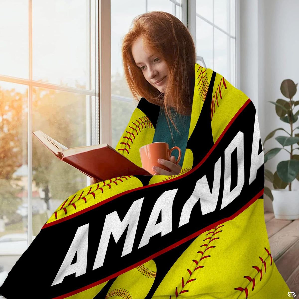 Folded view of softball pattern throw blanket showcasing yellow sports balls against black background.