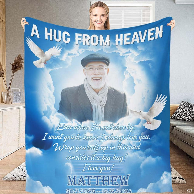 Woman holding up heavenly memorial blanket displaying soaring doves, sunlit clouds, and celestial blue sky artwork