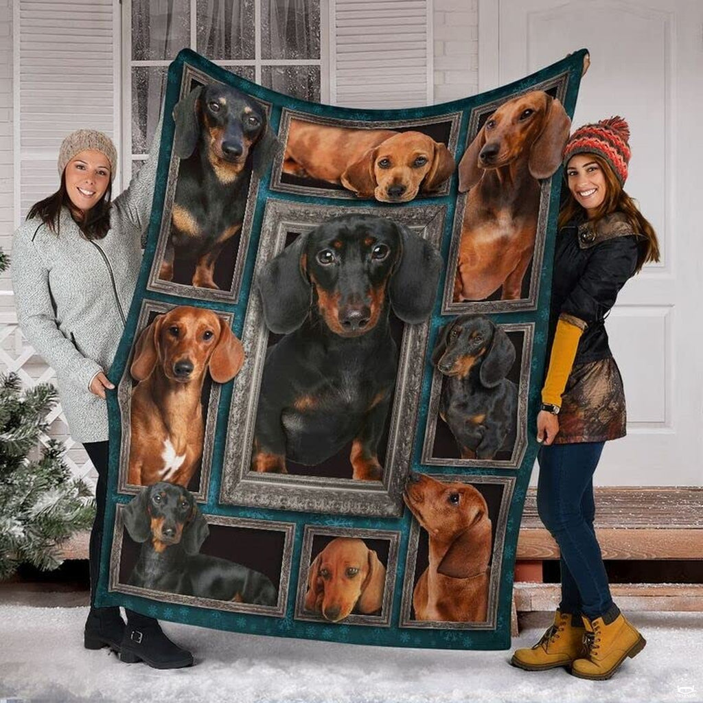 Two models displaying the Dachshund blanket outside a snowy winter home entrance.