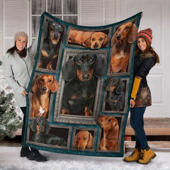 Two models displaying the Dachshund blanket outside a snowy winter home entrance.