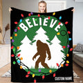 Brown Bigfoot walking in snowy forest framed by Christmas lights wreath and arched lettering, view 1.