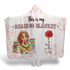 Pink botanical book lover throw blanket showing illustrated girl, stacked novels, and scarlet carnation