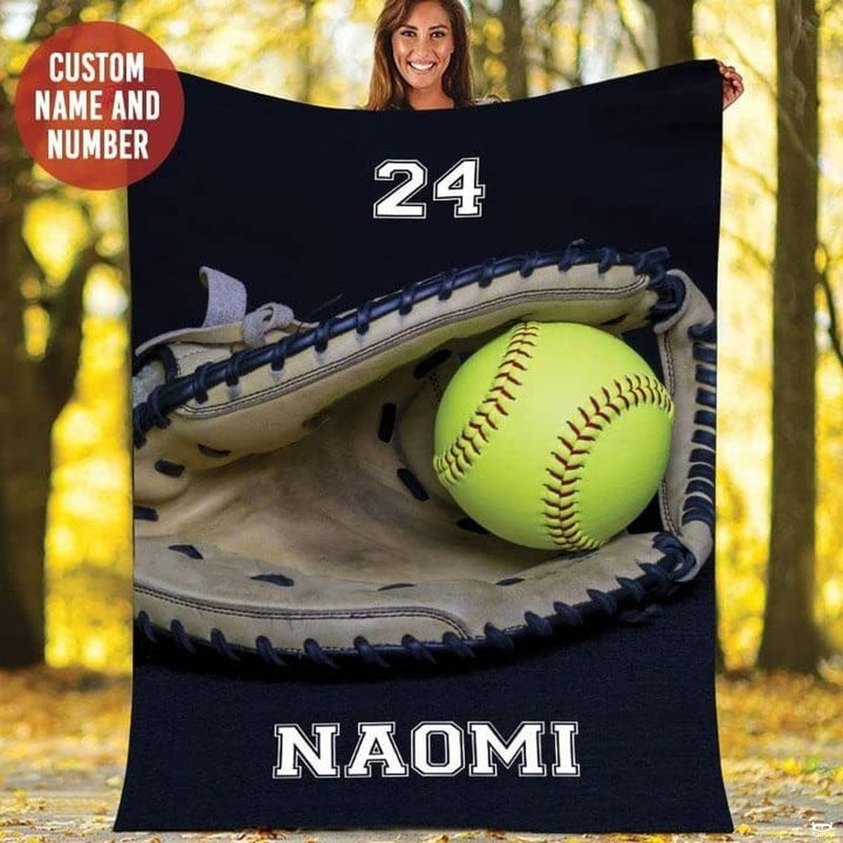 Person holding up the navy fastpitch glove and ball print in an autumn forest.