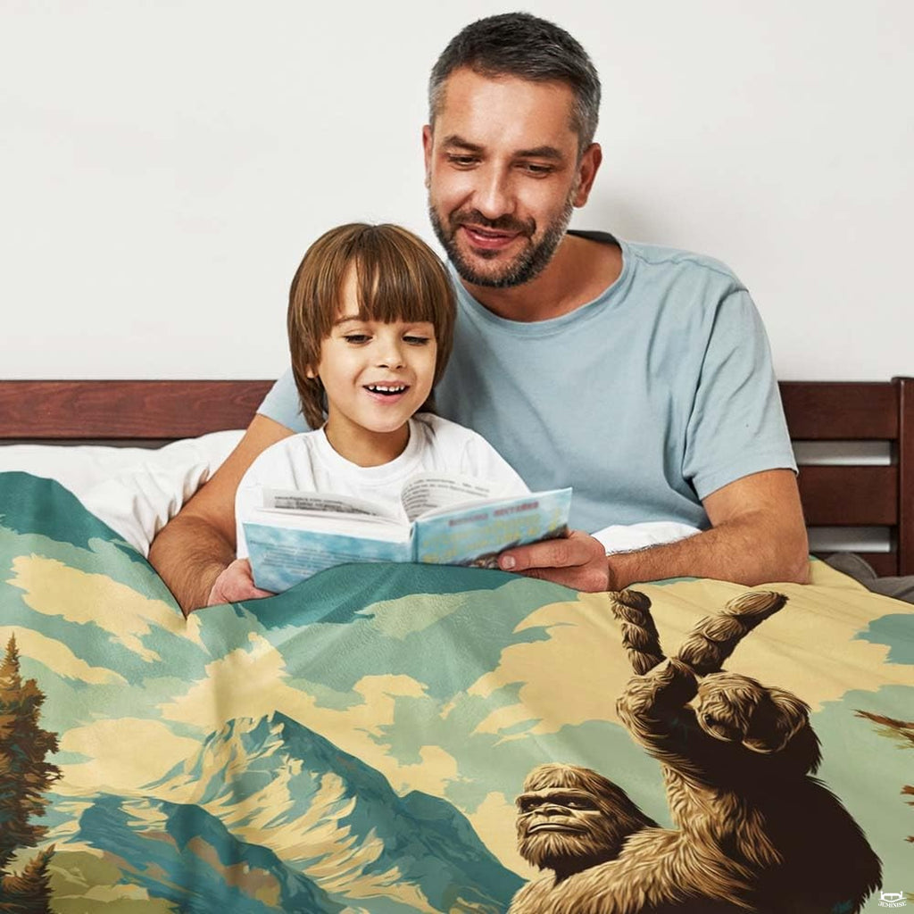 Father and son reading book under bigfoot peace sign mountain blanket