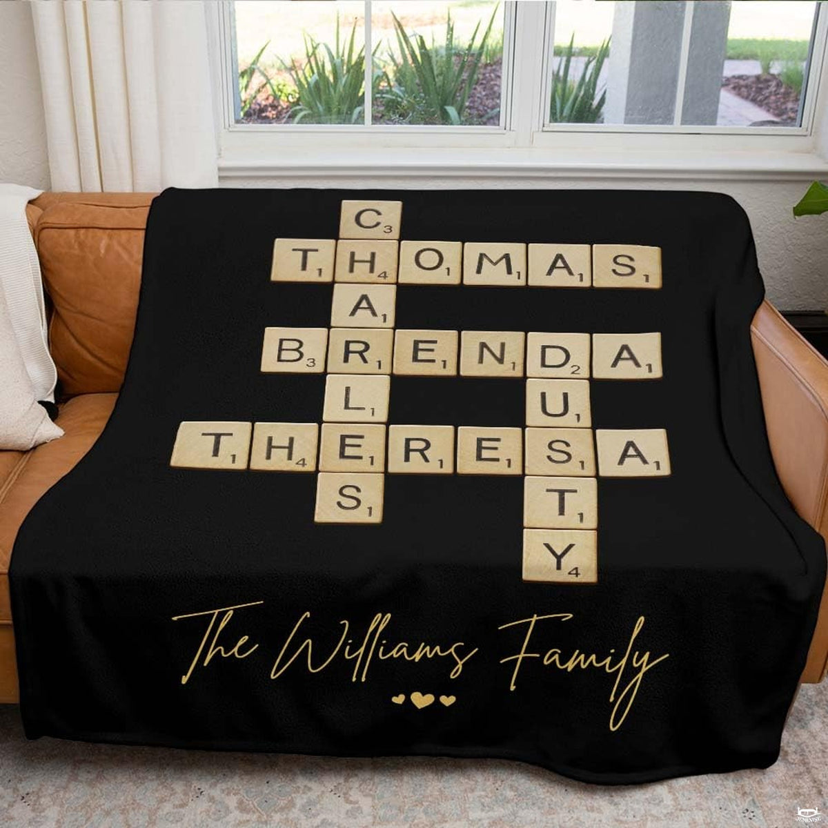 Living room sofa setting displaying black crossword puzzle throw blanket draped across furniture.