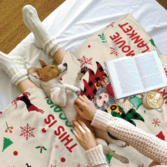 Cozy bed setting featuring puppy napping beside folded reindeer Christmas movie throw blanket.