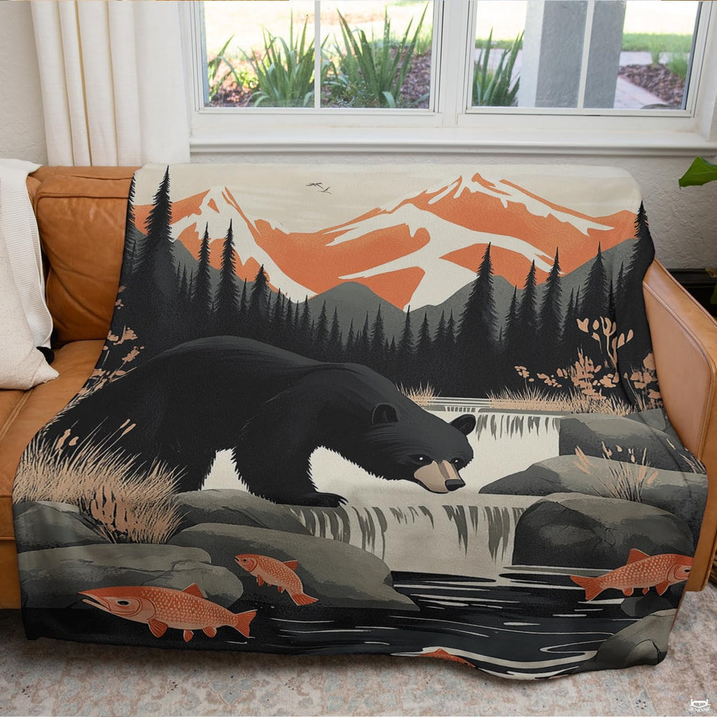 Close up of black bear throw blanket highlighting swimming salmon, waterfall rapids, and pine trees