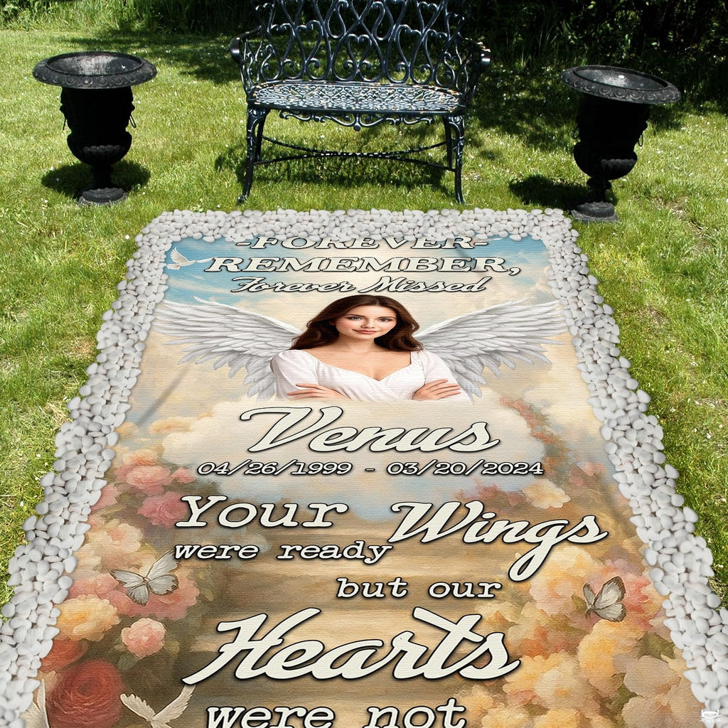 Outdoor cemetery display of memorial angel grave blanket laid across green lawn bordered by stones.