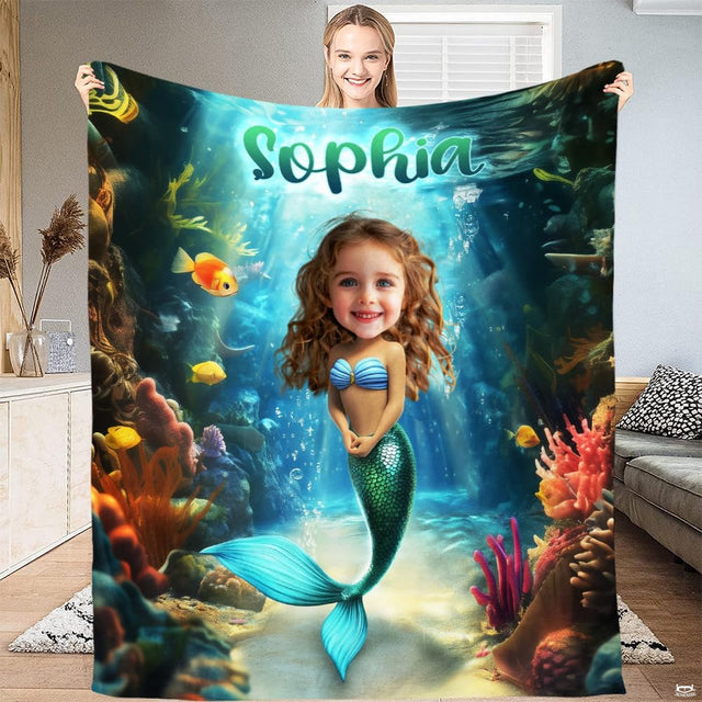 Woman displaying colorful underwater mermaid graphic throw blanket with coral reef and tropical fish.