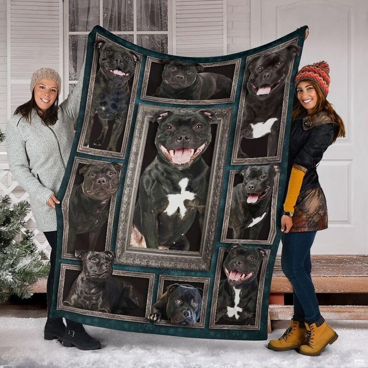 Two models displaying the Staffordshire Bull Terrier blanket outside a snowy winter home entrance.