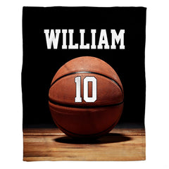 Basketball on polished hardwood gym floor under dramatic overhead spotlight, view 1.