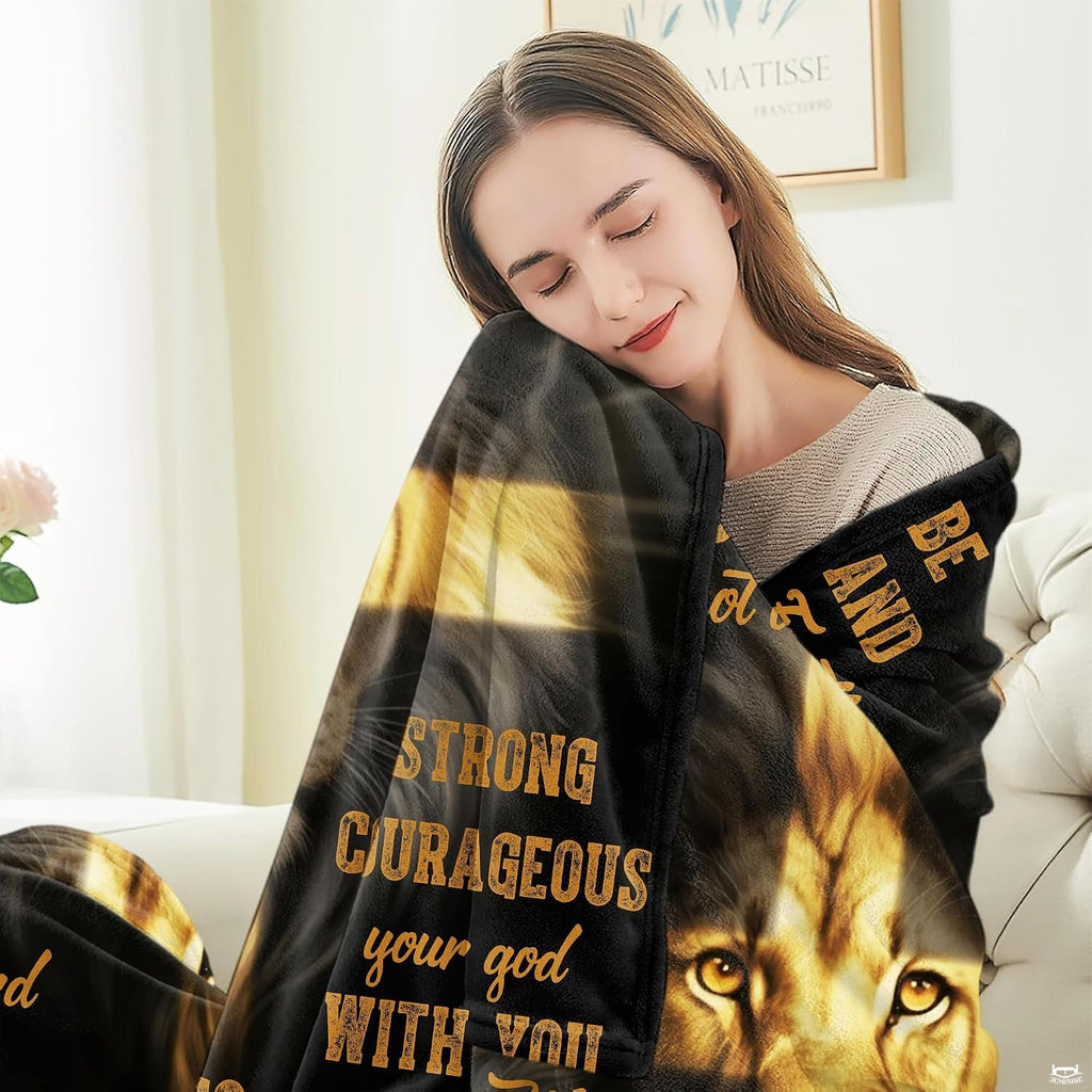 Person seated indoors relaxing while wrapped in a golden lion and cross devotional throw.