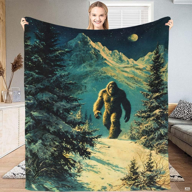 Snowy alpine Bigfoot mountain throw blanket featuring Sasquatch trekking through winter woods under moon