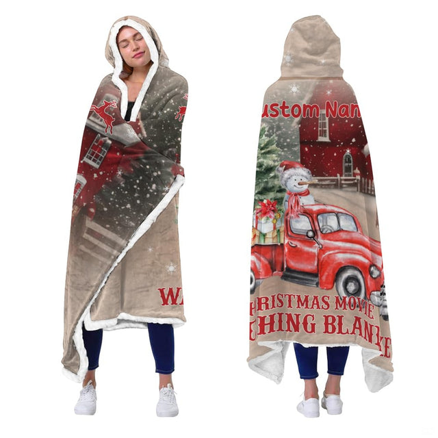 Close up illustration of a vintage red truck surrounded by falling white snowflakes and red barns.