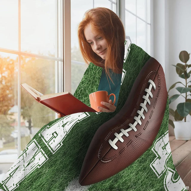 Young woman reading by sunny window wrapped in vibrant green football turf throw blanket