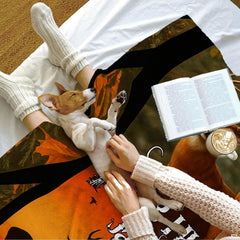 Lifestyle scene showing a small dog on the printed autumn wildlife textile next to an open book.