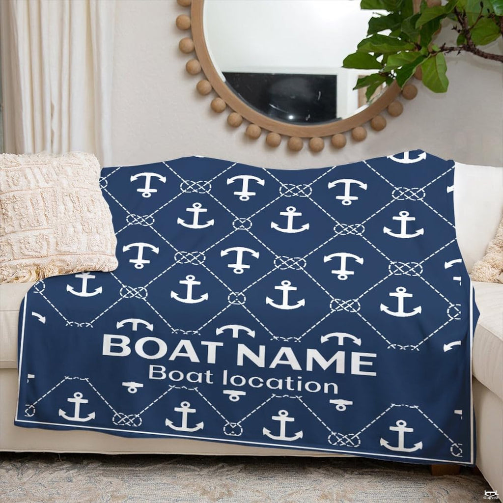 Nautical anchor graphic throw blanket folded across white living room couch beneath round mirror.