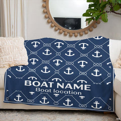Nautical anchor graphic throw blanket folded across white living room couch beneath round mirror.