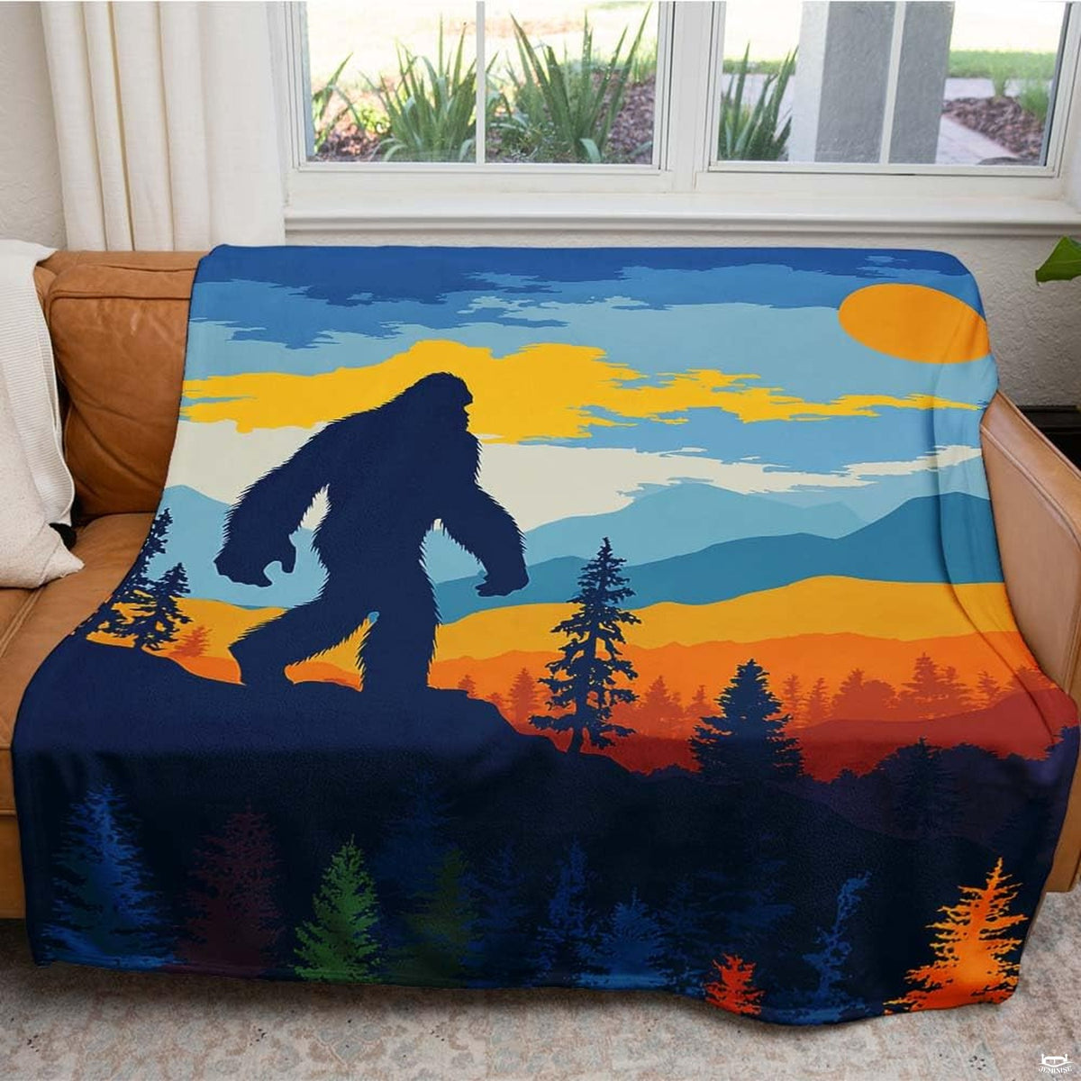 Close-up of Bigfoot silhouette artwork, evergreen forest, and glowing sun on wilderness themed bedding.