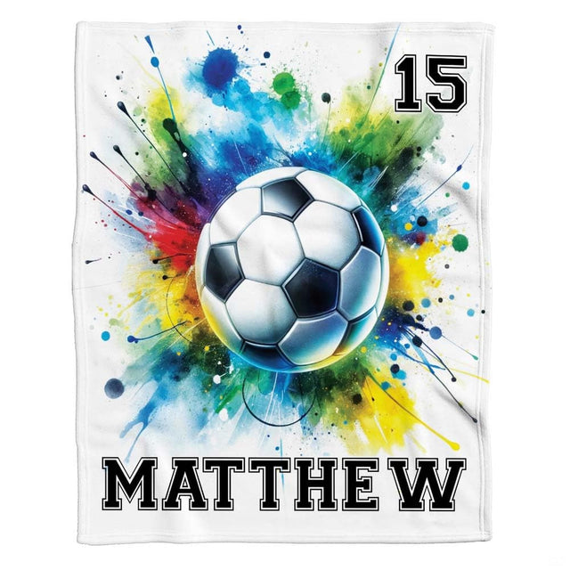 Close up of vibrant watercolor paint splatters and drips surrounding soccer ball art in rich crimson and turquoise.
