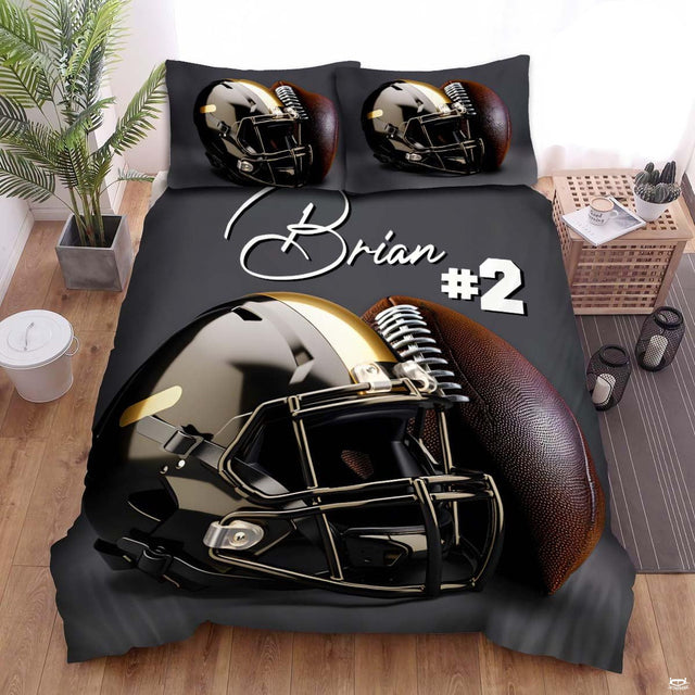 Bedding set featuring a glossy black and metallic gold football helmet resting on dark charcoal background.