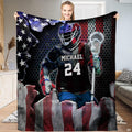 Patriotic lacrosse player blanket featuring athlete breaking through American flag over honeycomb backdrop.