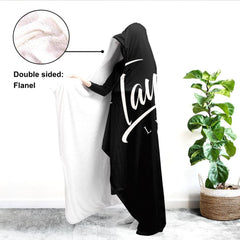 Side view of soccer sports blanket draped over shoulders displaying white inner lining beside indoor greenery.