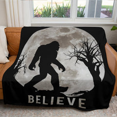Full moon Sasquatch blanket neatly draped across a living room couch in front of a window.